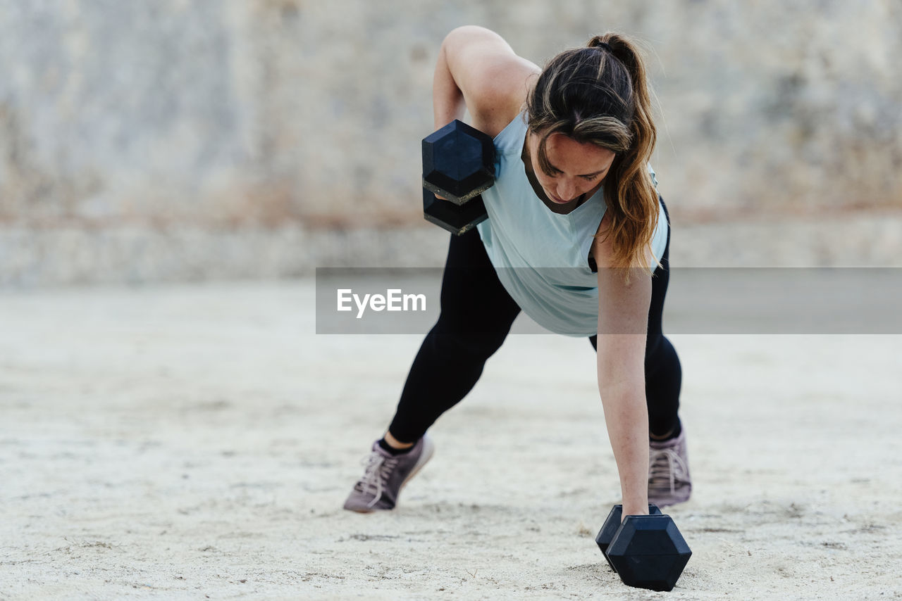 Young woman doing weight training in urban environment.