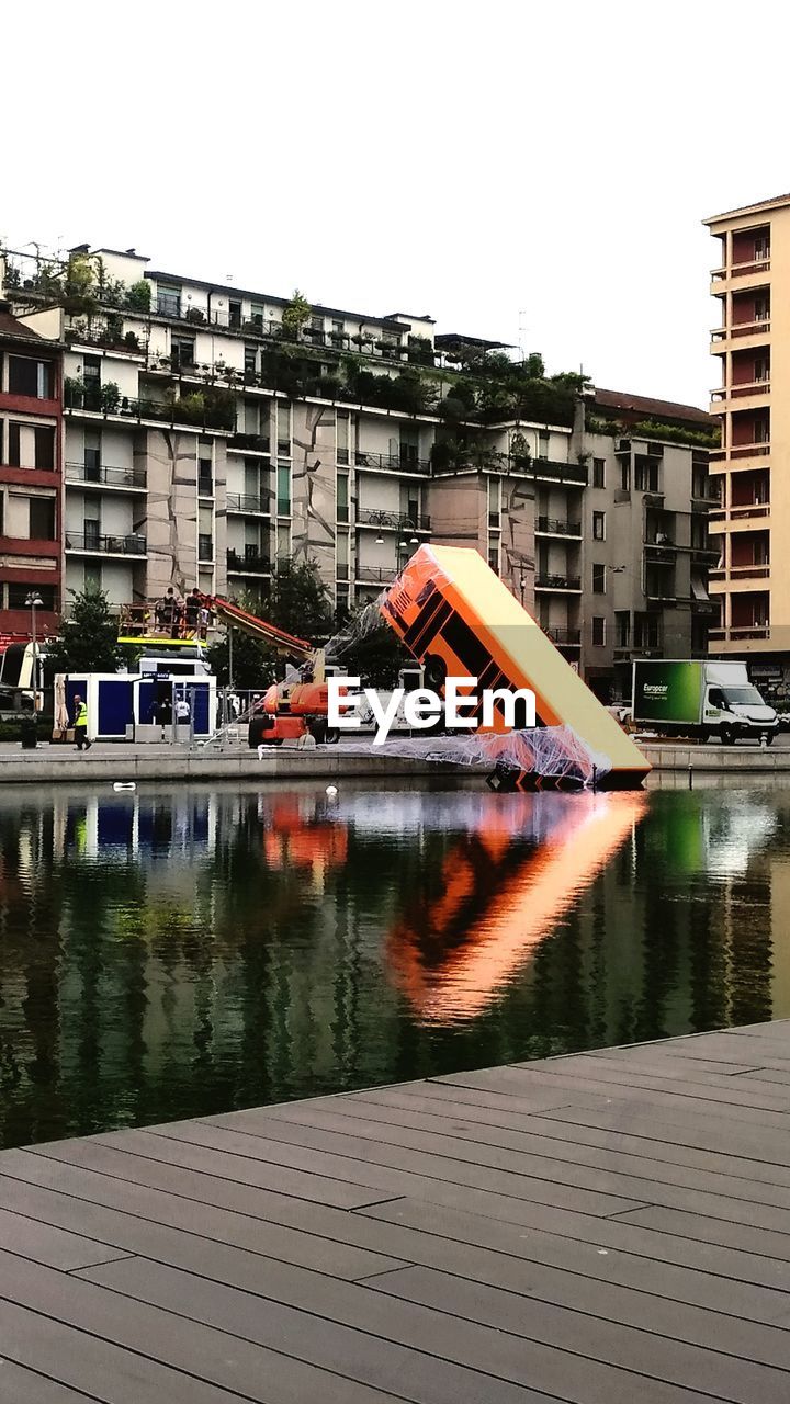 REFLECTION OF BUILDINGS IN LAKE AGAINST SKY