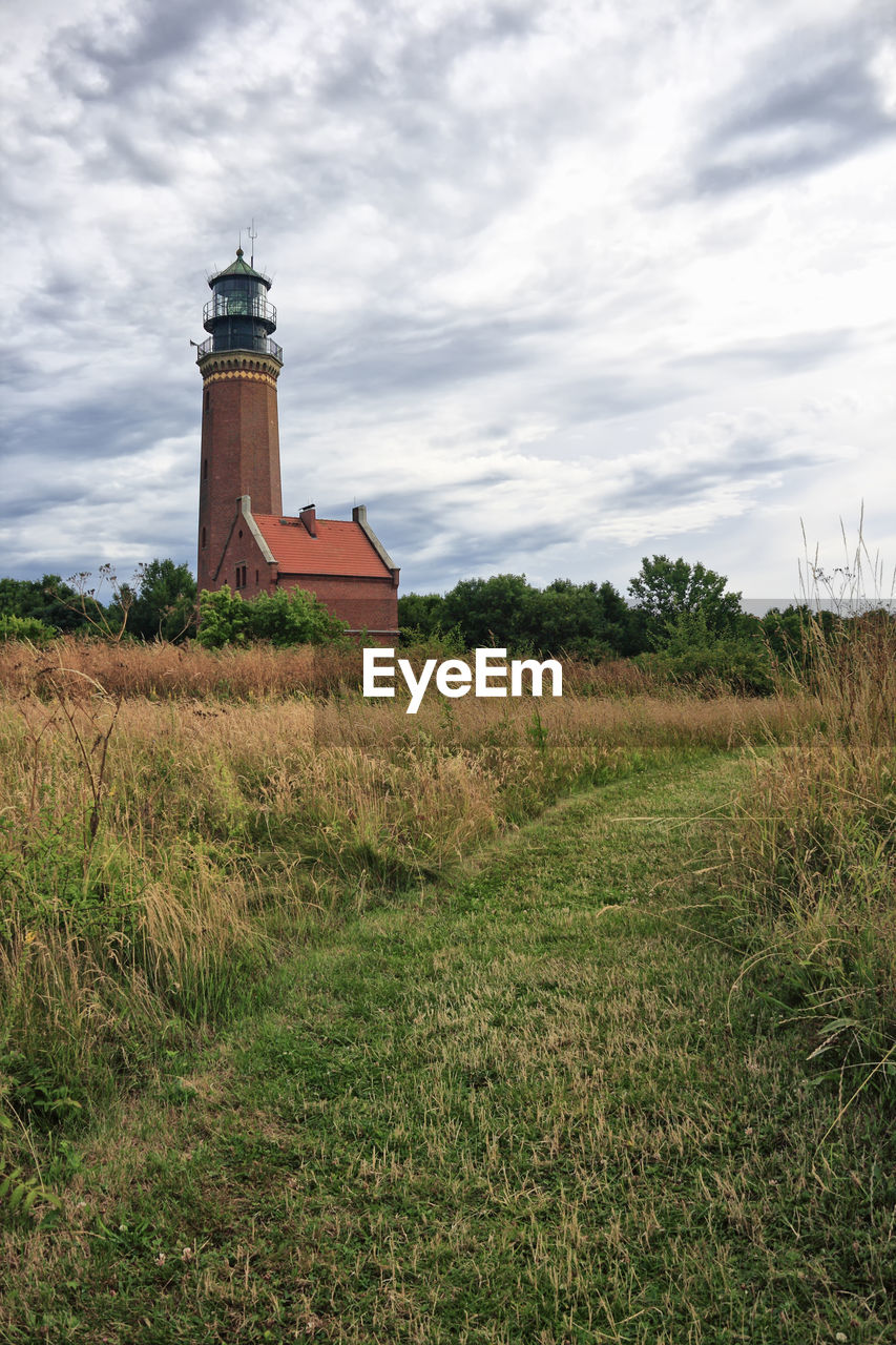 LIGHTHOUSE AMIDST FIELD AGAINST SKY