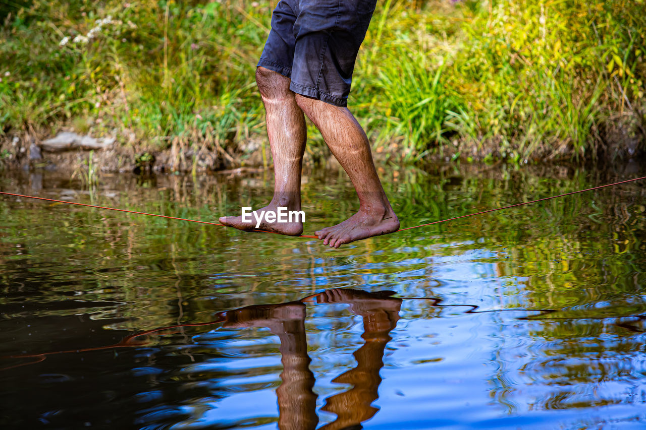 Low section of man standing in lake