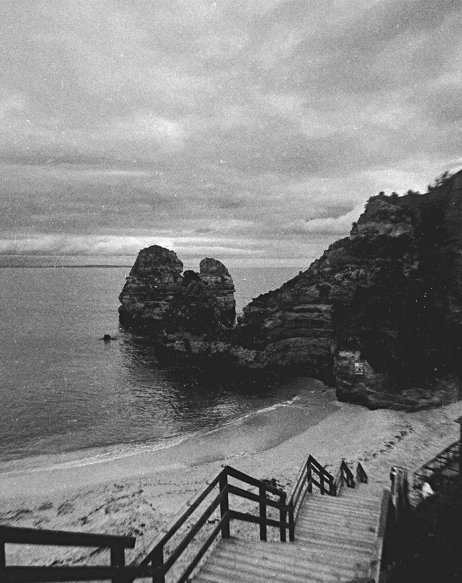 water, sky, black and white, sea, monochrome photography, railing, nature, monochrome, land, beach, staircase, beauty in nature, scenics - nature, cloud, coast, rock, tranquility, no people, tranquil scene, mountain, day, architecture, steps and staircases, outdoors, travel destinations