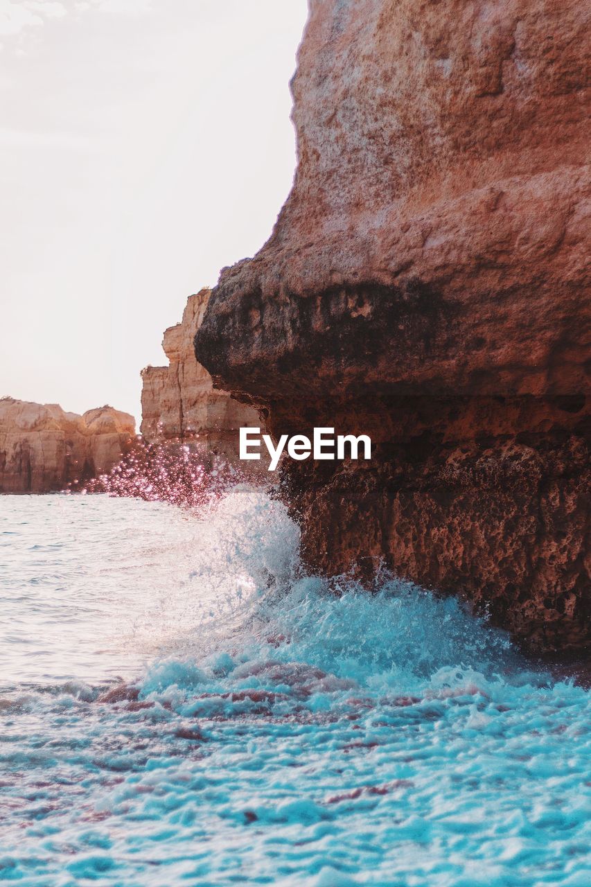 Sea waves splashing on rock formation at beach