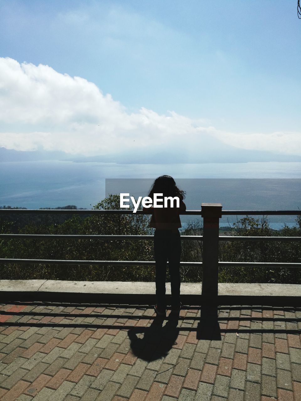 REAR VIEW OF A MAN OVERLOOKING SEA