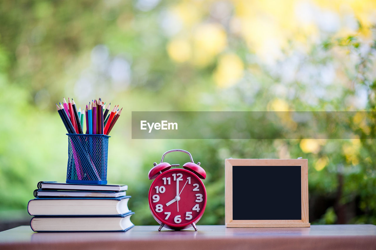 Colorful pencils with books and alarm clock on table