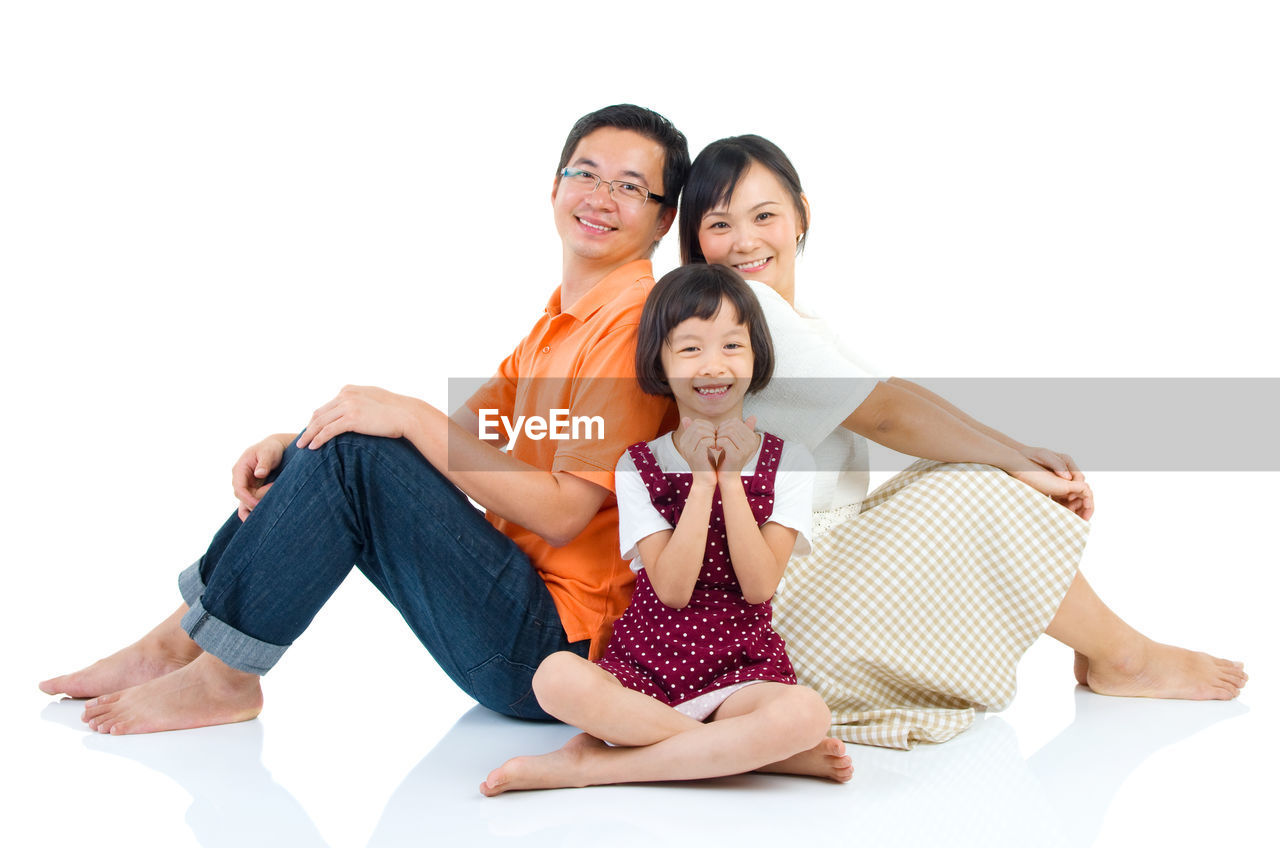 Mother and father with daughter sitting against white background