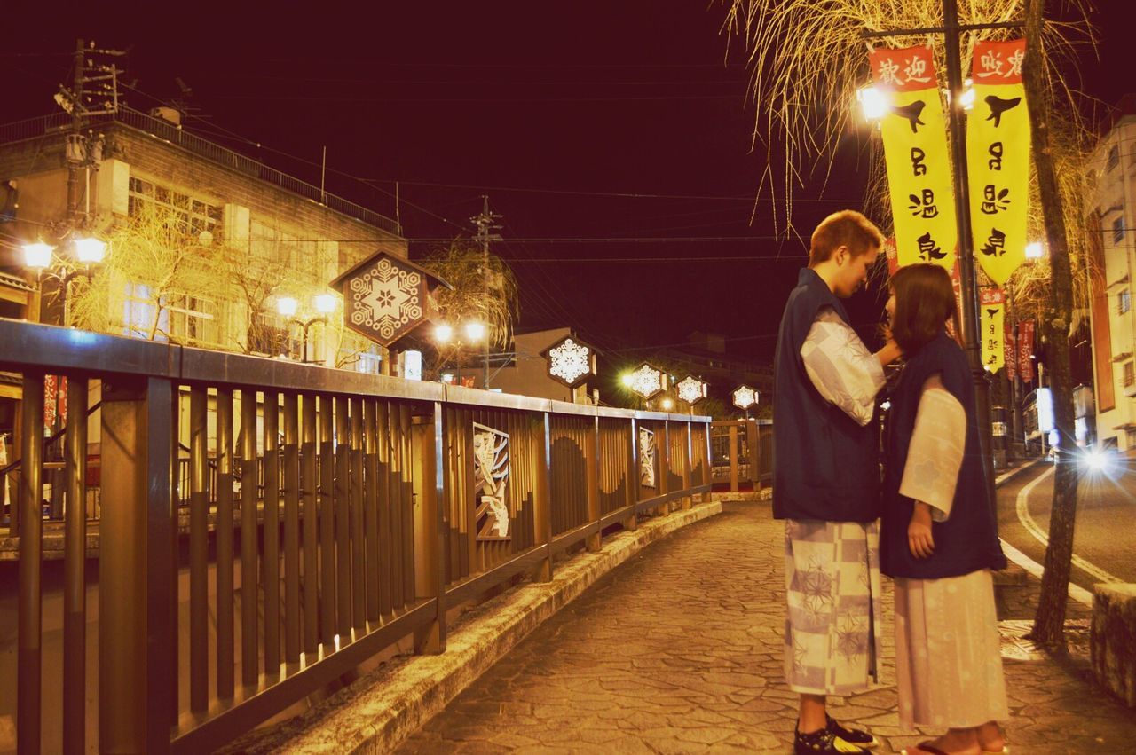 COUPLE IN ILLUMINATED CITY AT NIGHT DURING WINTER AT DUSK