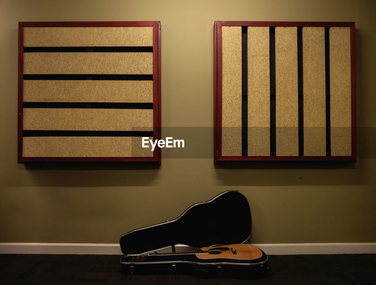 Acoustic guitar on floor against wall