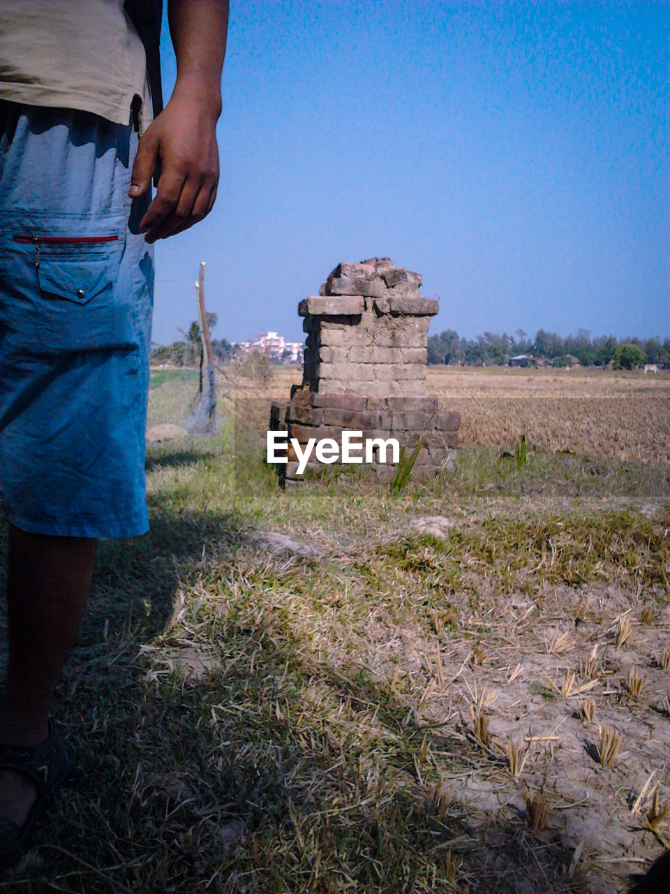 Low section of man standing on field against sky