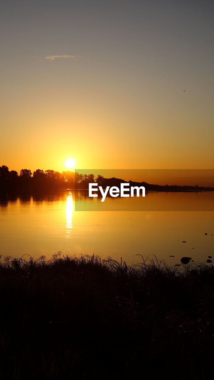 SCENIC VIEW OF LAKE AGAINST SKY AT SUNSET