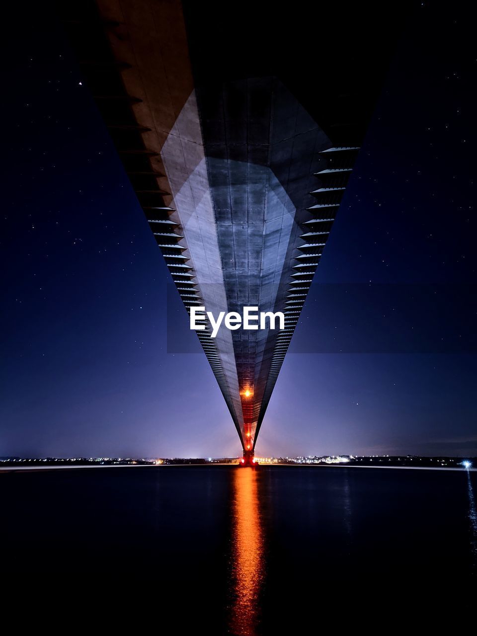 Illuminated bridge over river against sky at night