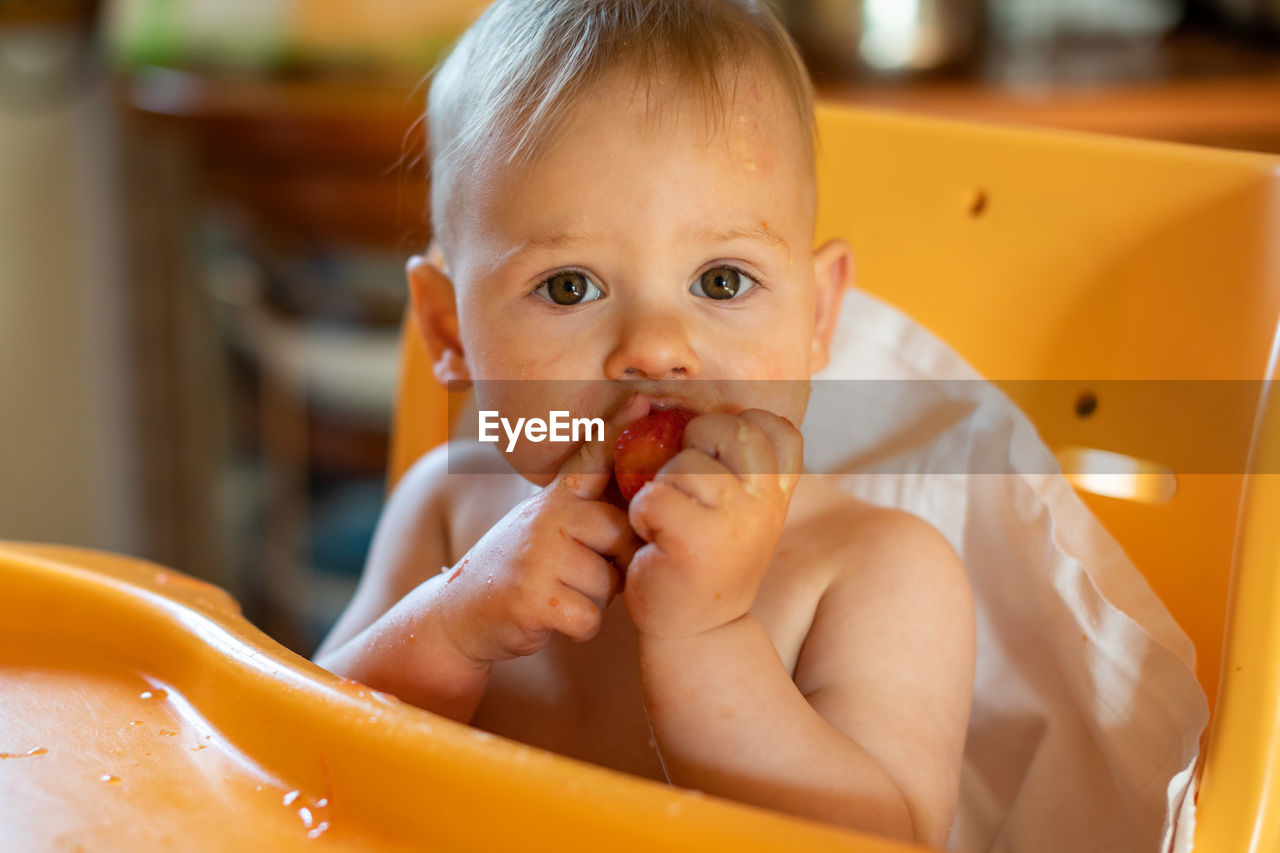 Portrait of cute baby girl eating fruit