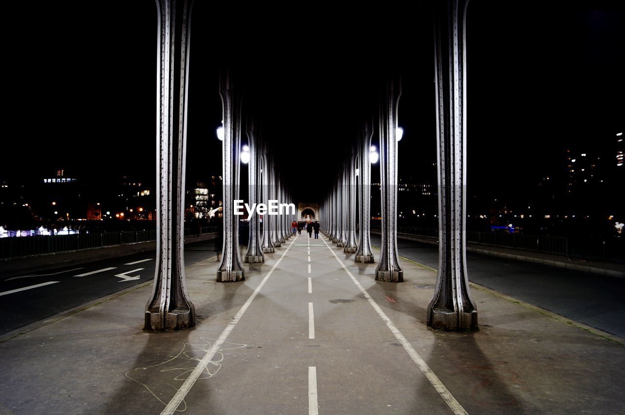 View of illuminated road under bridge in city at night