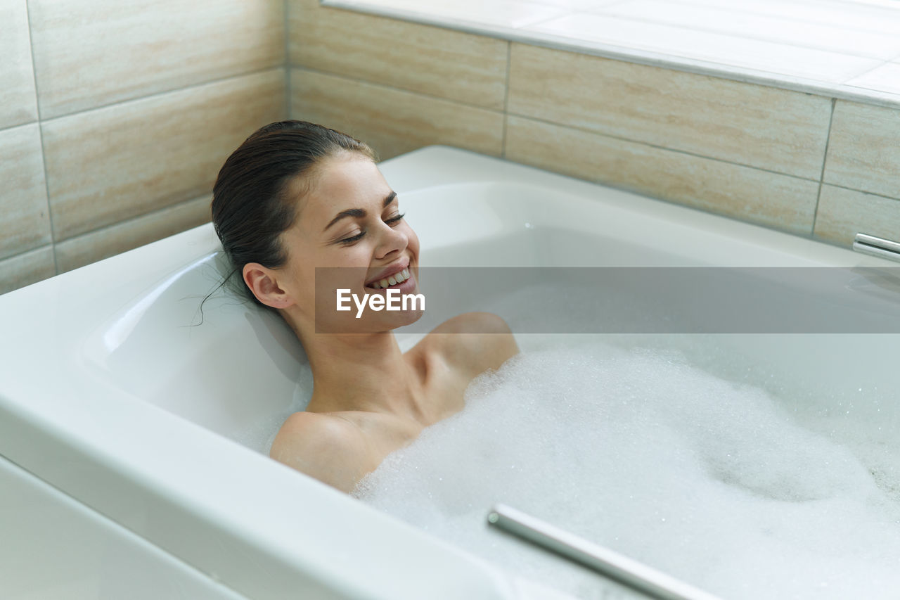 Young woman sitting in bathroom at home