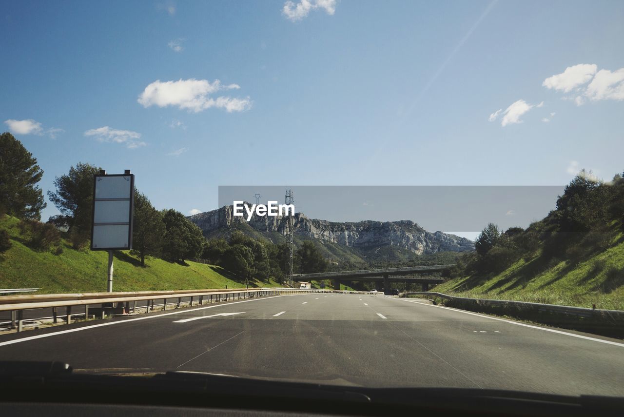 Road and mountains against sky seen through car windshield