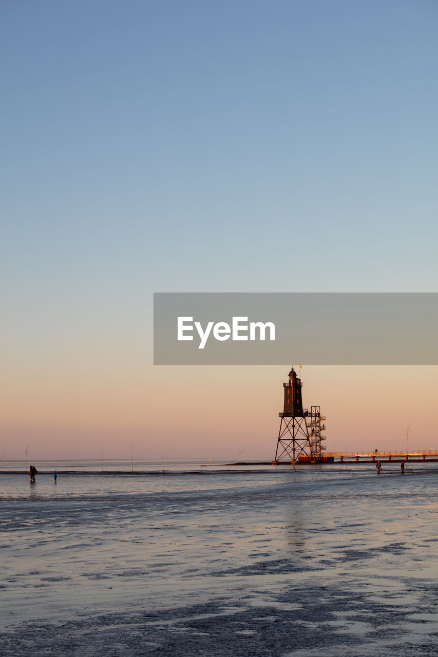 Historical lighthouse of obereversand during sunset and low tide in mud flat of the north sea.