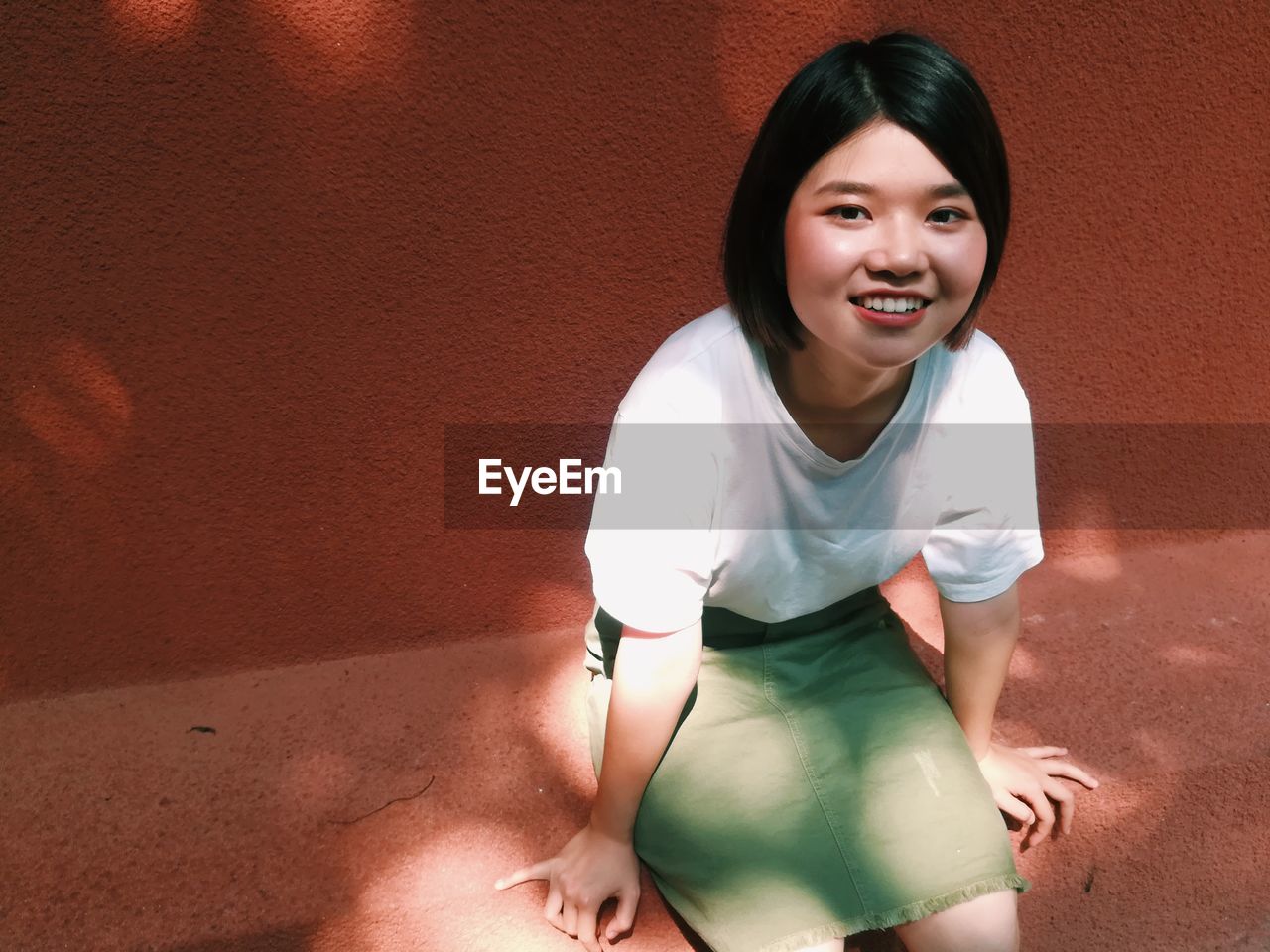 PORTRAIT OF SMILING YOUNG WOMAN STANDING OUTDOORS