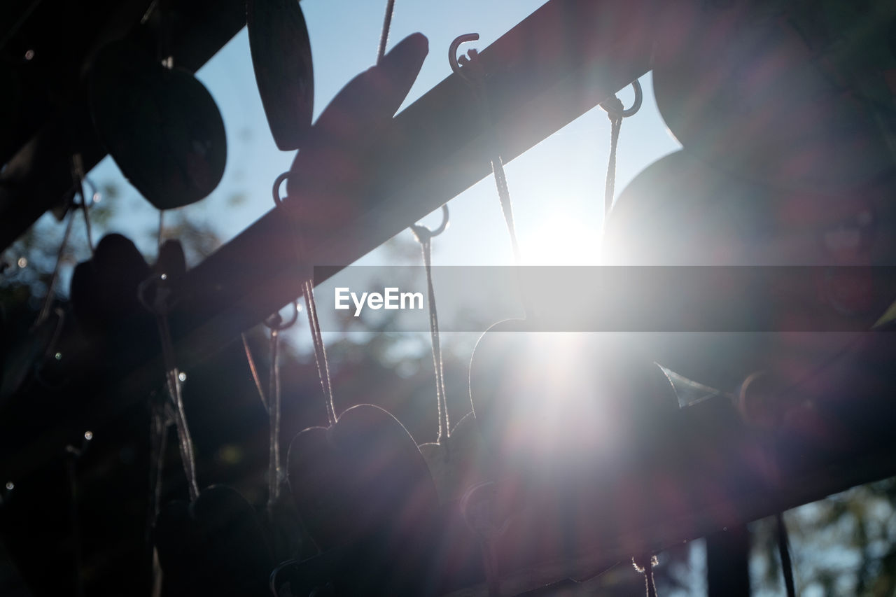 Low angle view of decorations hanging on railing against bright sun