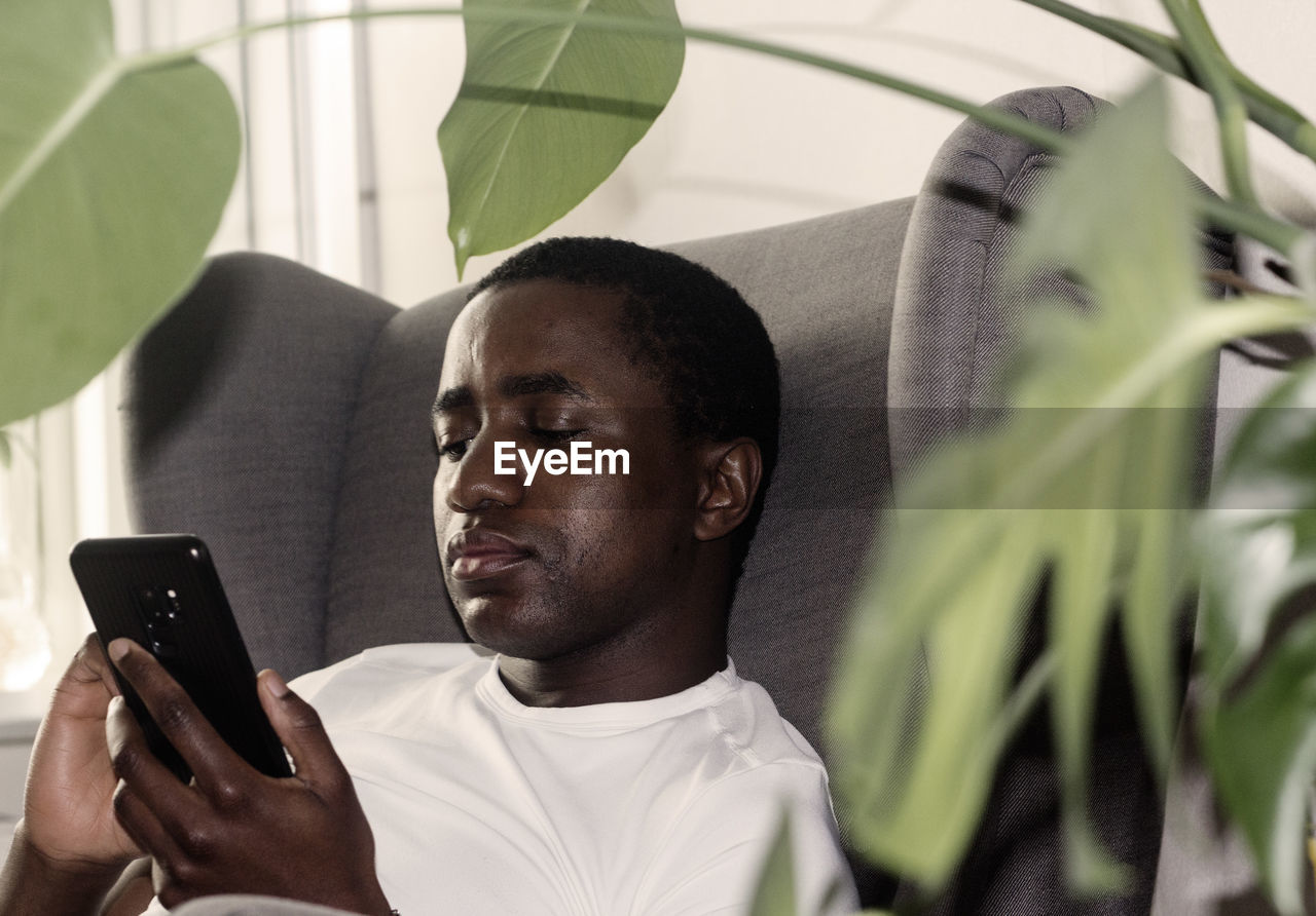 Man using smart phone while sitting on armchair