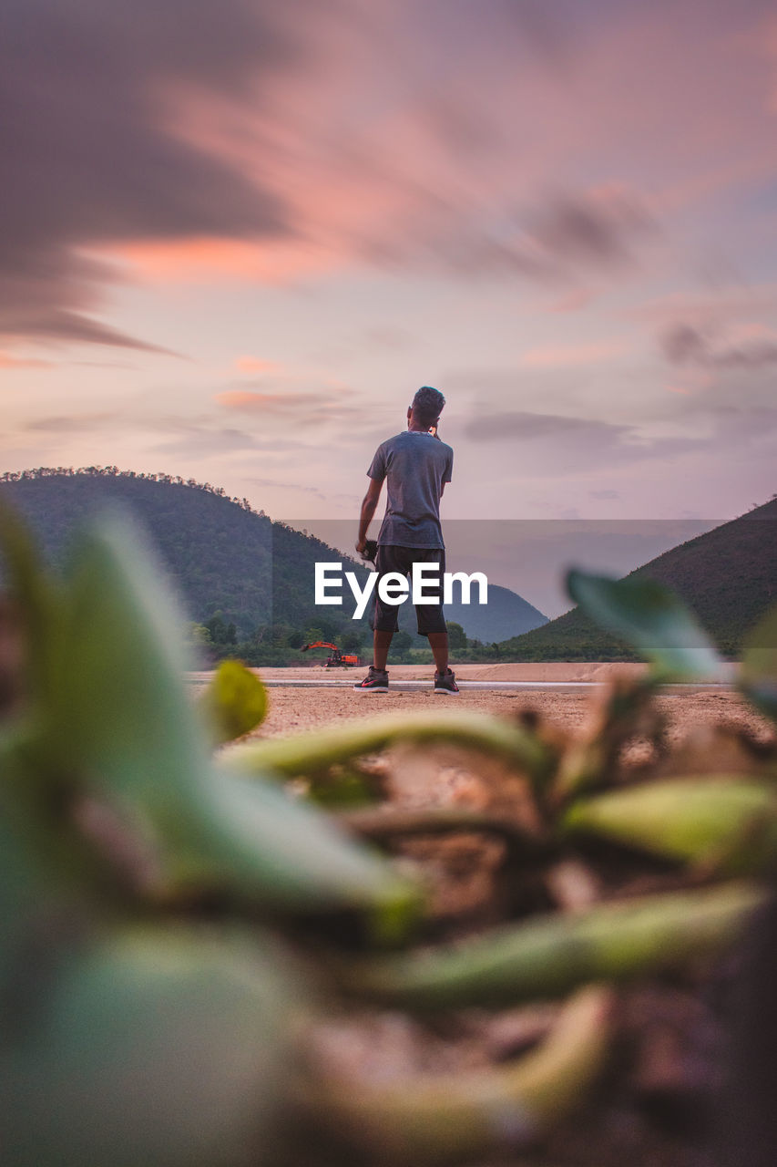 Rear view of man standing on land against mountain