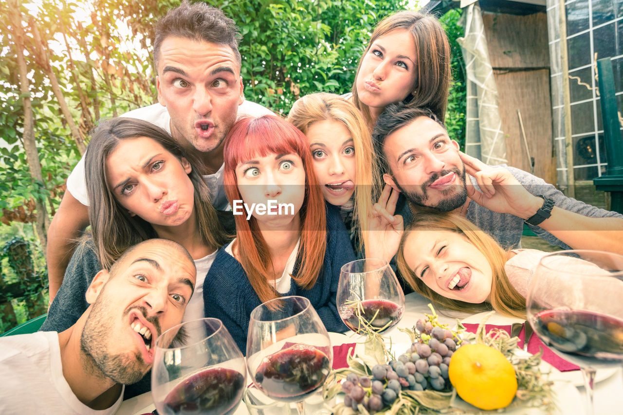 Portrait of friends making faces at dining table