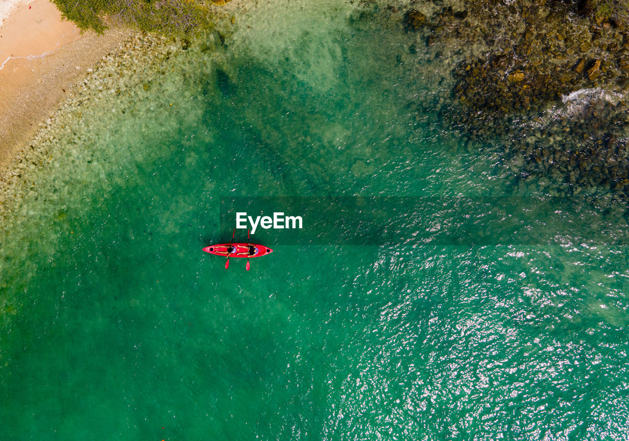 The top view of two tourist paddling their red kayak at the beautiful blue seashore in summer