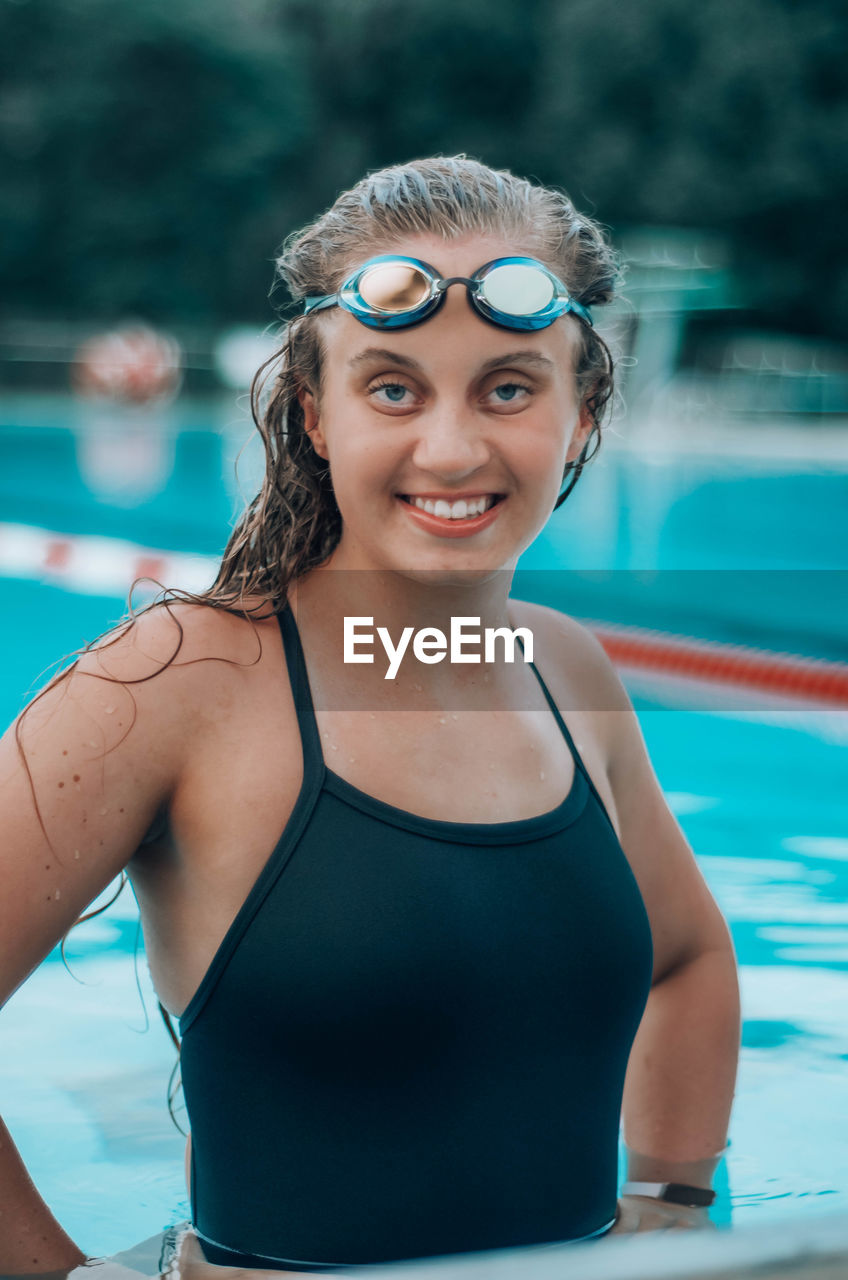 PORTRAIT OF SMILING WOMAN SWIMMING IN POOL