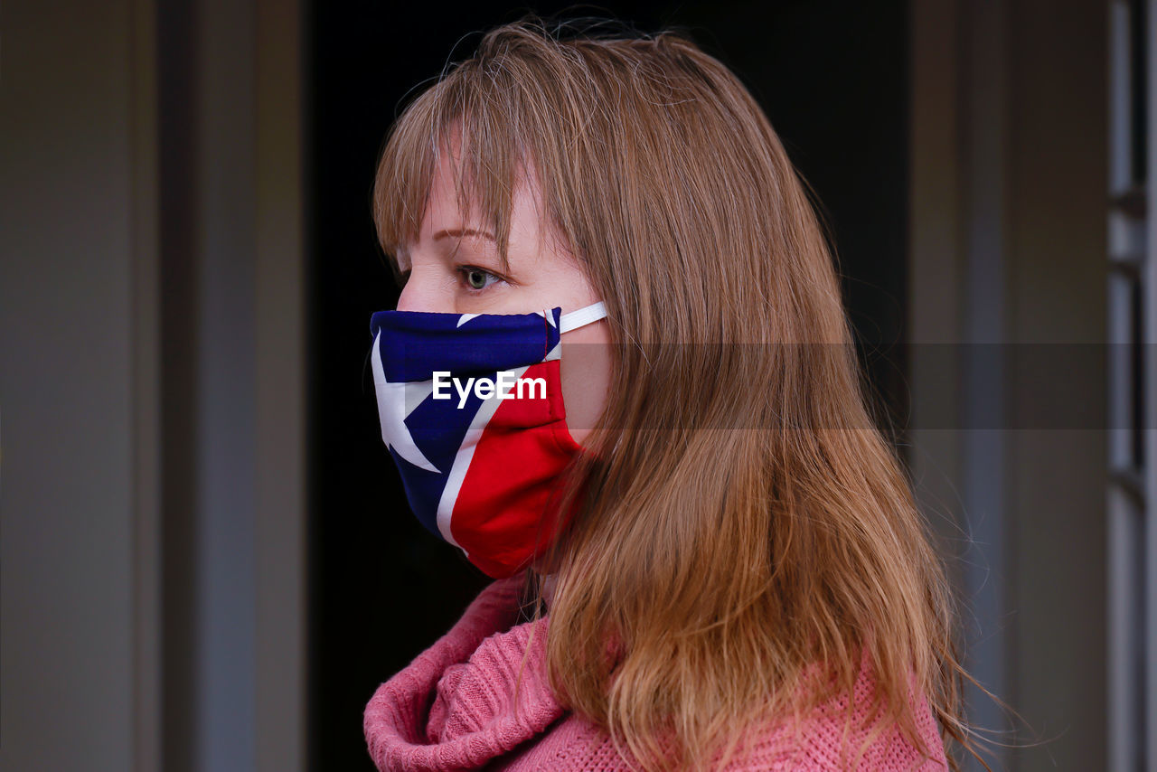 A 40 year old blonde woman is wearing a fabric mask. it protects against corona virus. homemade 