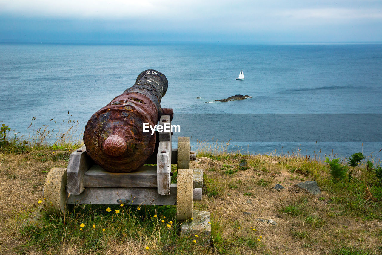 ABANDONED RUSTY METAL BY SEA AGAINST SKY