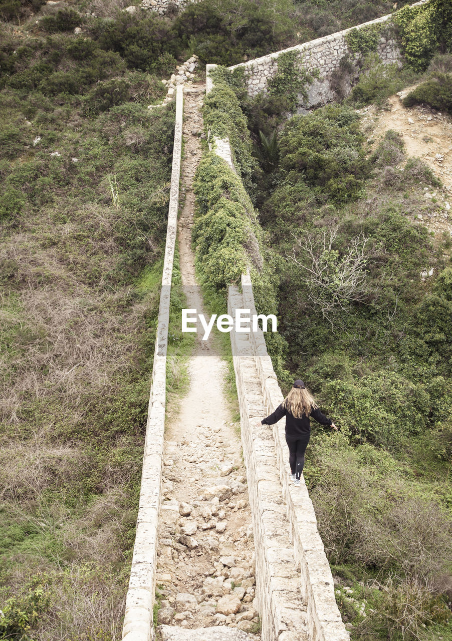 High angle view of woman walking on retaining wall
