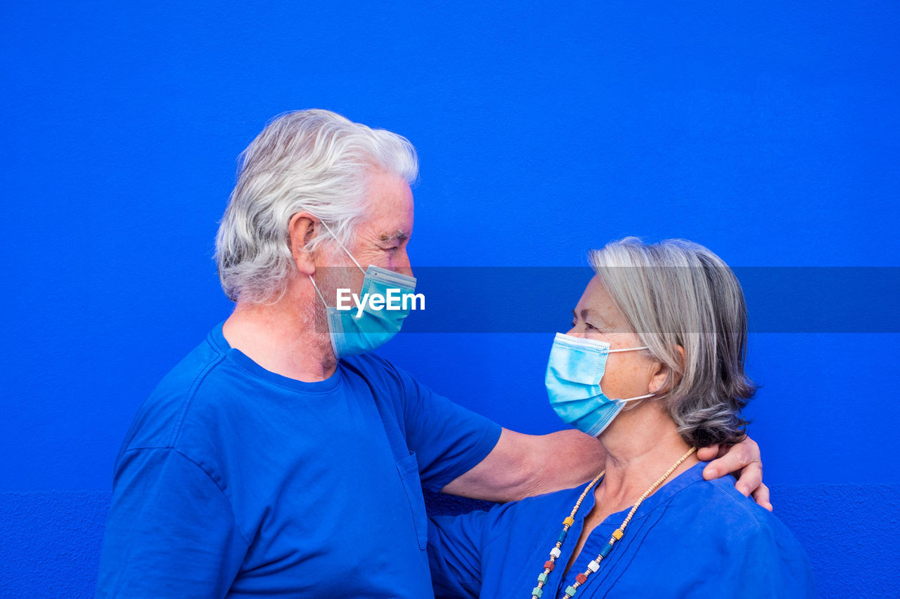 Smiling senior couple standing against blue background