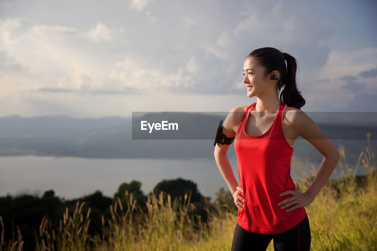 Young woman exercising on mountain against cloudy sky during sunset