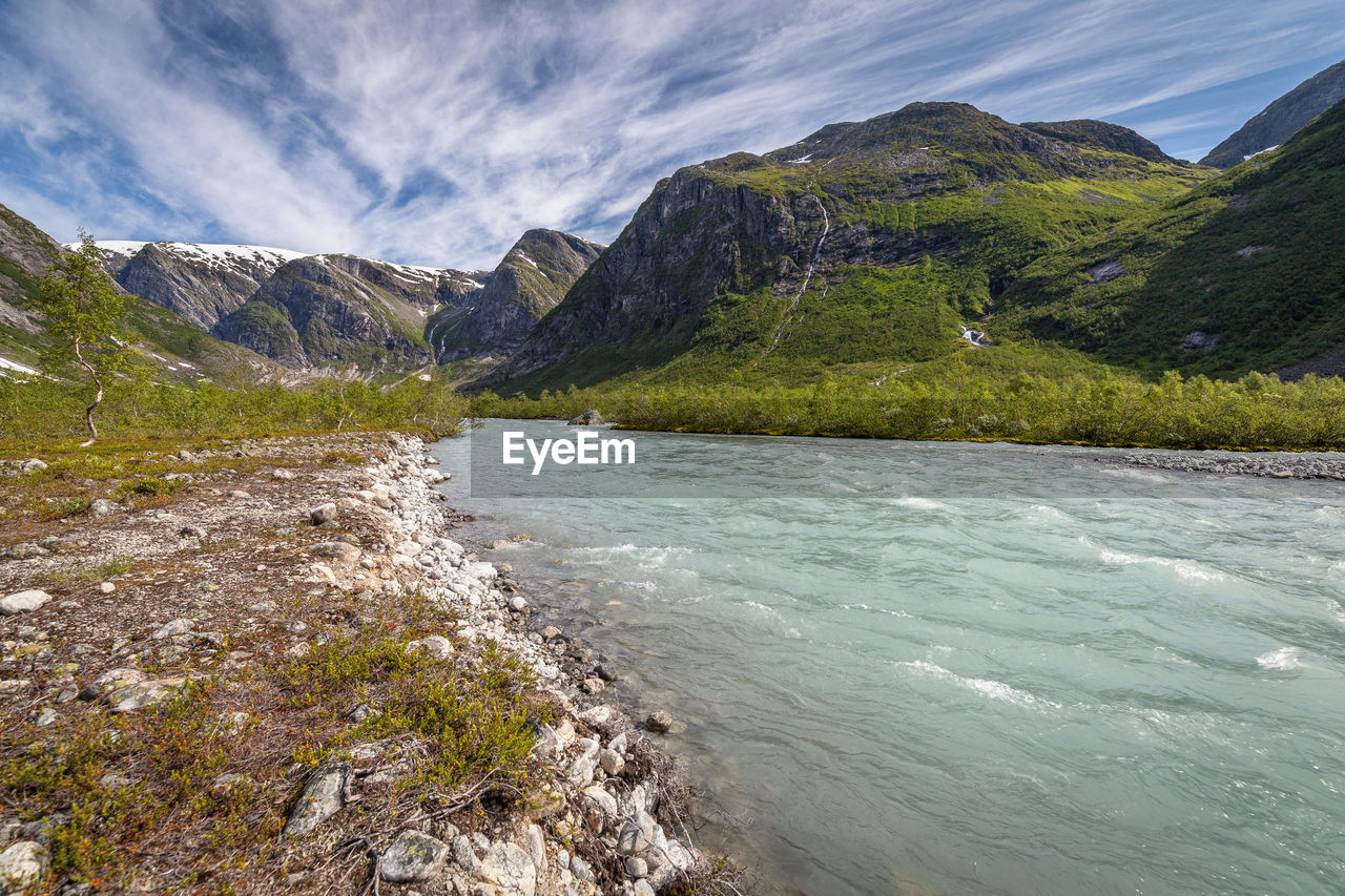 Scenic view of sea by mountains against sky