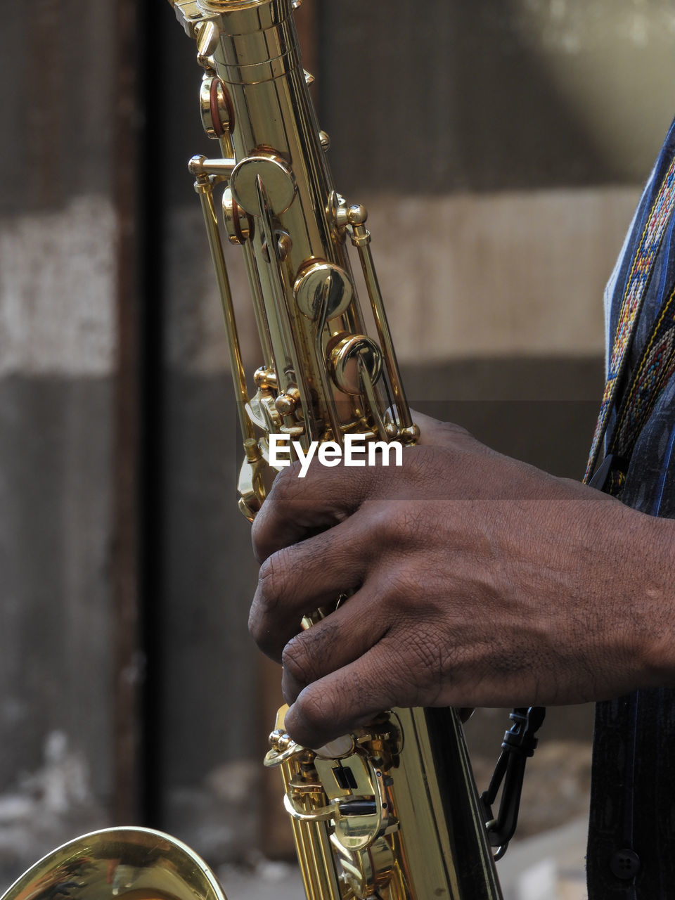 Cropped hand of musician playing saxophone outdoors