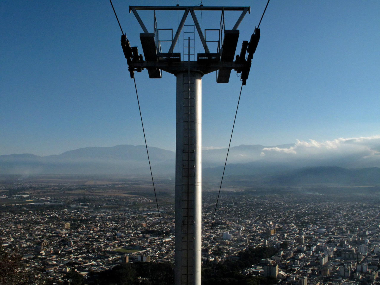 Overhead cable car tower in city against sky