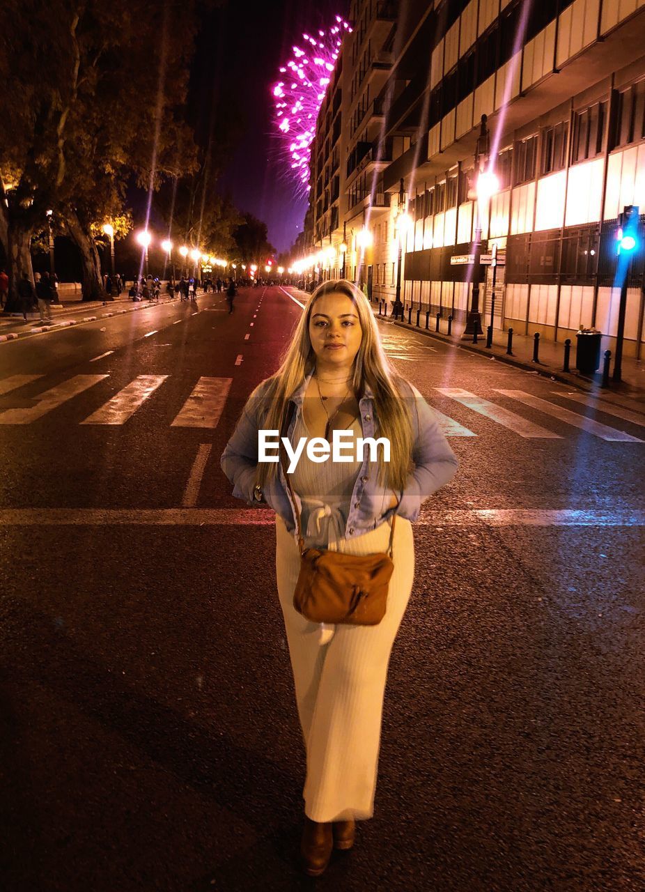 Portrait of woman standing on city street at night