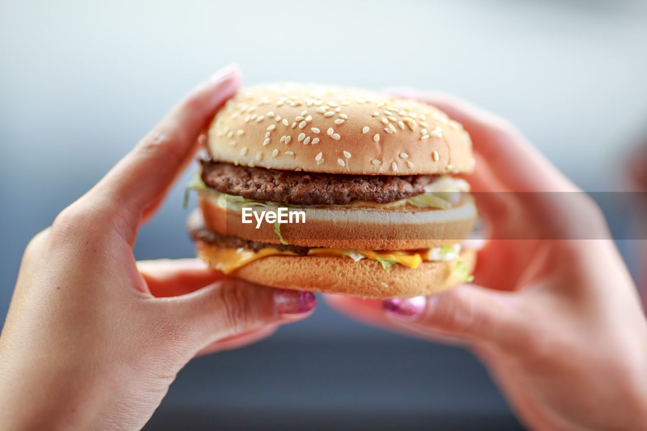 Close-up of hands holding hamburger outdoors