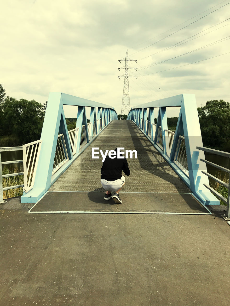 MAN ON BRIDGE AGAINST SKY DURING SUNSET