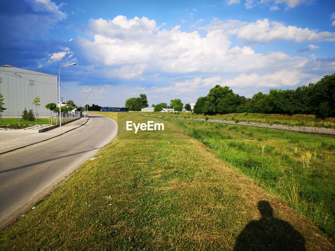 Road amidst grassy field against sky