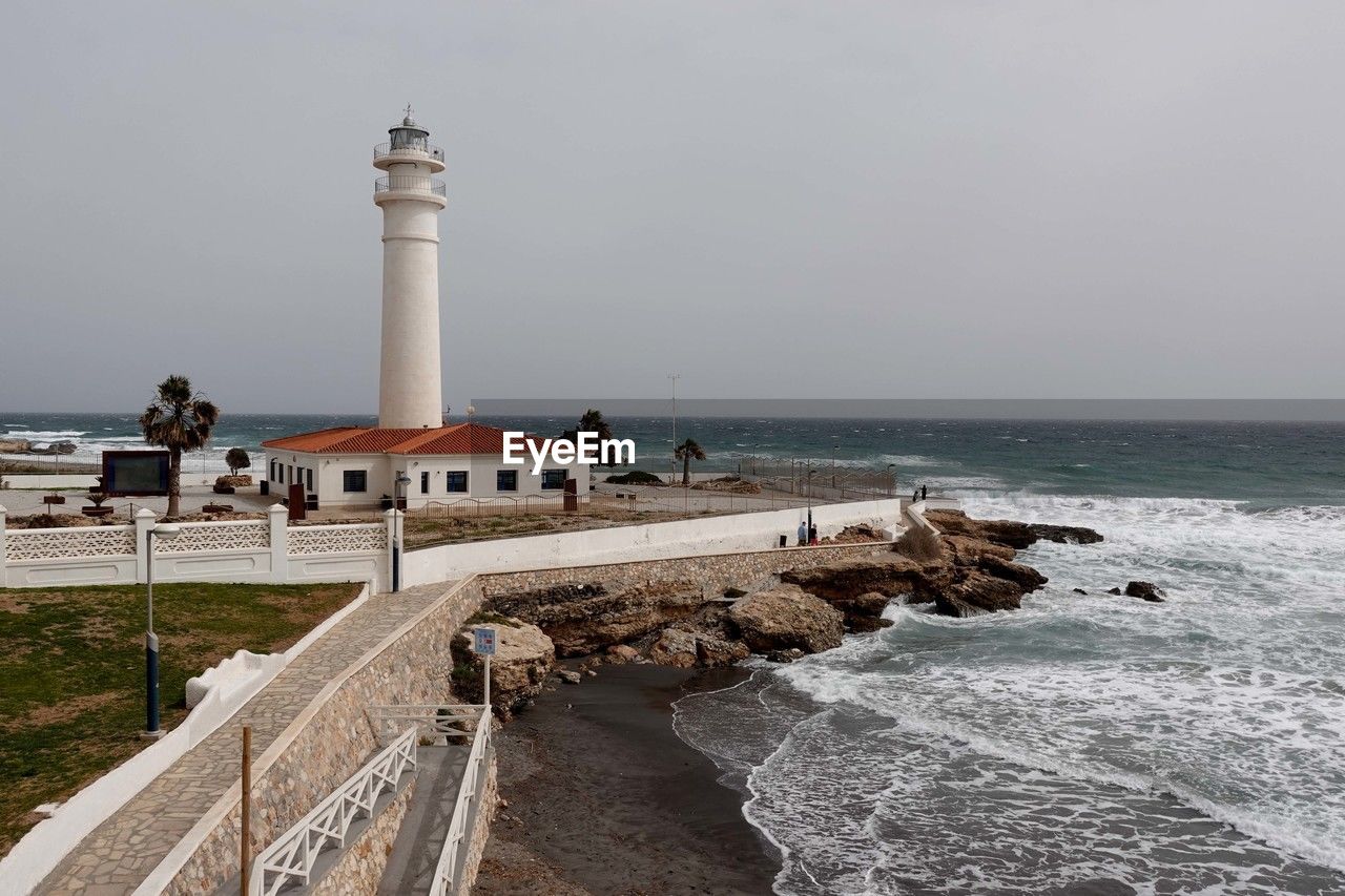 Lighthouse by sea against sky