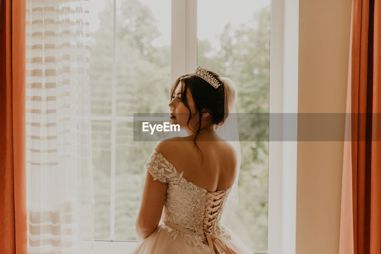 young woman standing against curtain