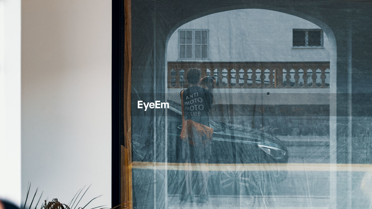 REFLECTION OF PEOPLE ON GLASS WINDOW IN CITY