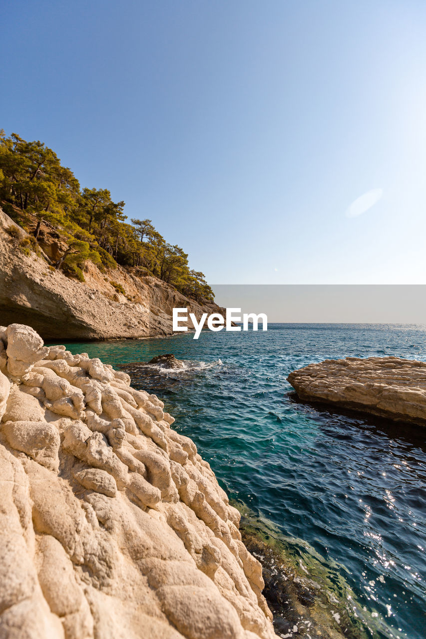 Large white stones in azure water against the background of rocks