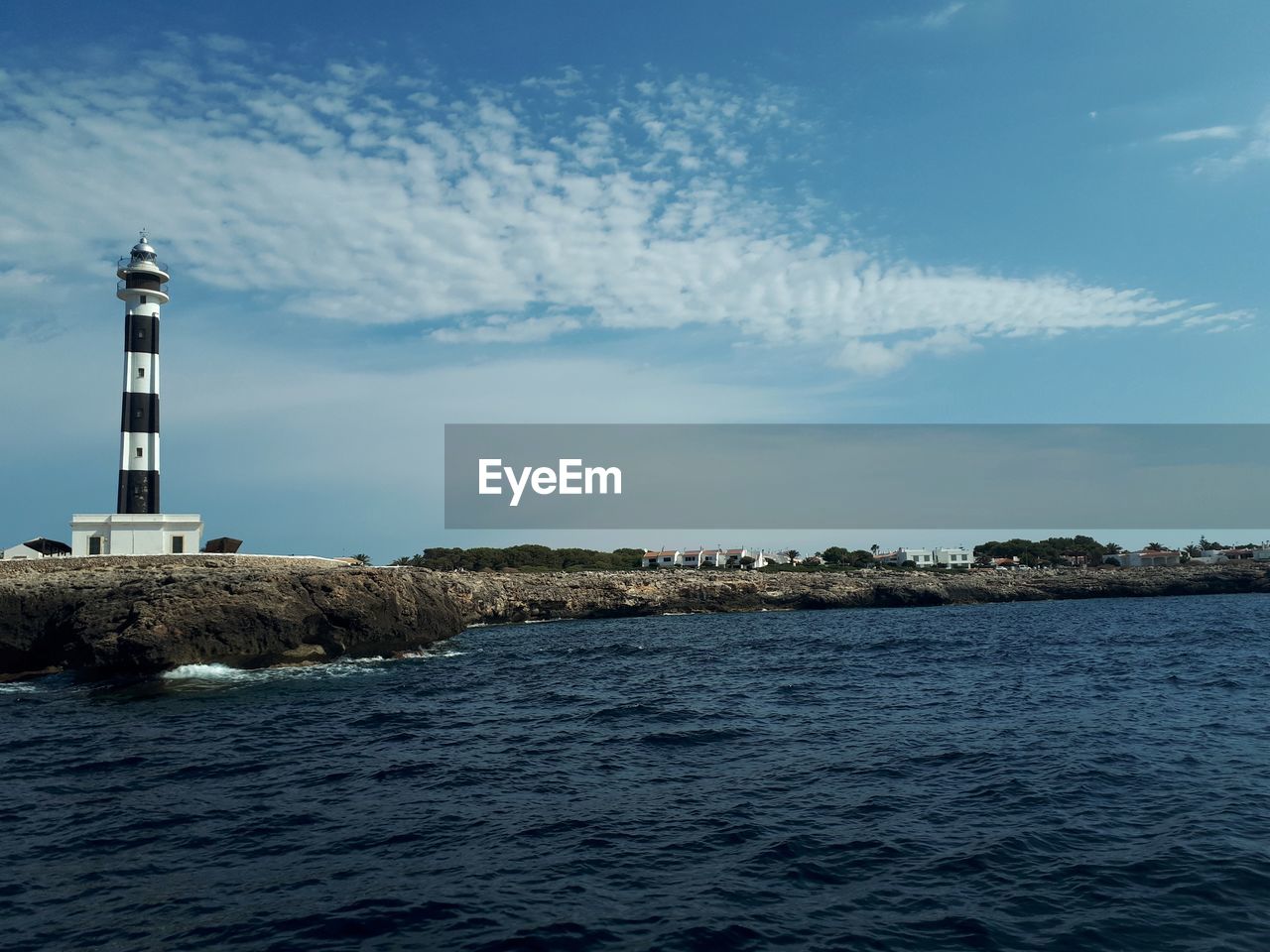 Menorca - spain / lighthouse amidst sea and buildings against sky