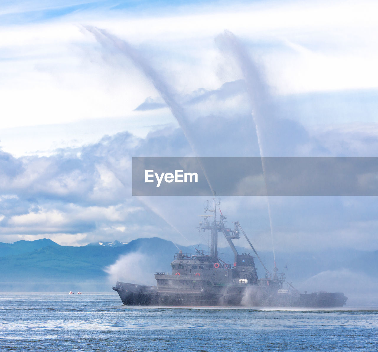 Fire hose boat spraying water on kamchatka on paciic ocean