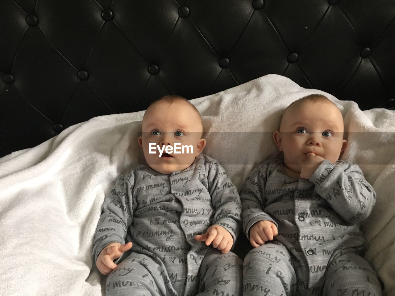 Cute twin baby boys sitting on bed