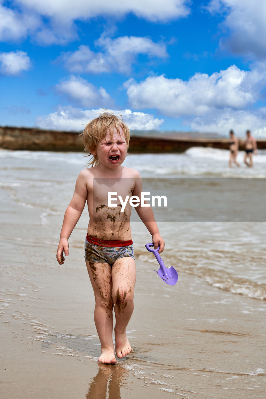 rear view of shirtless boy playing in sea against sky