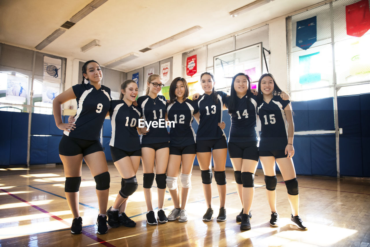 Front view of happy female volleyball team standing in court