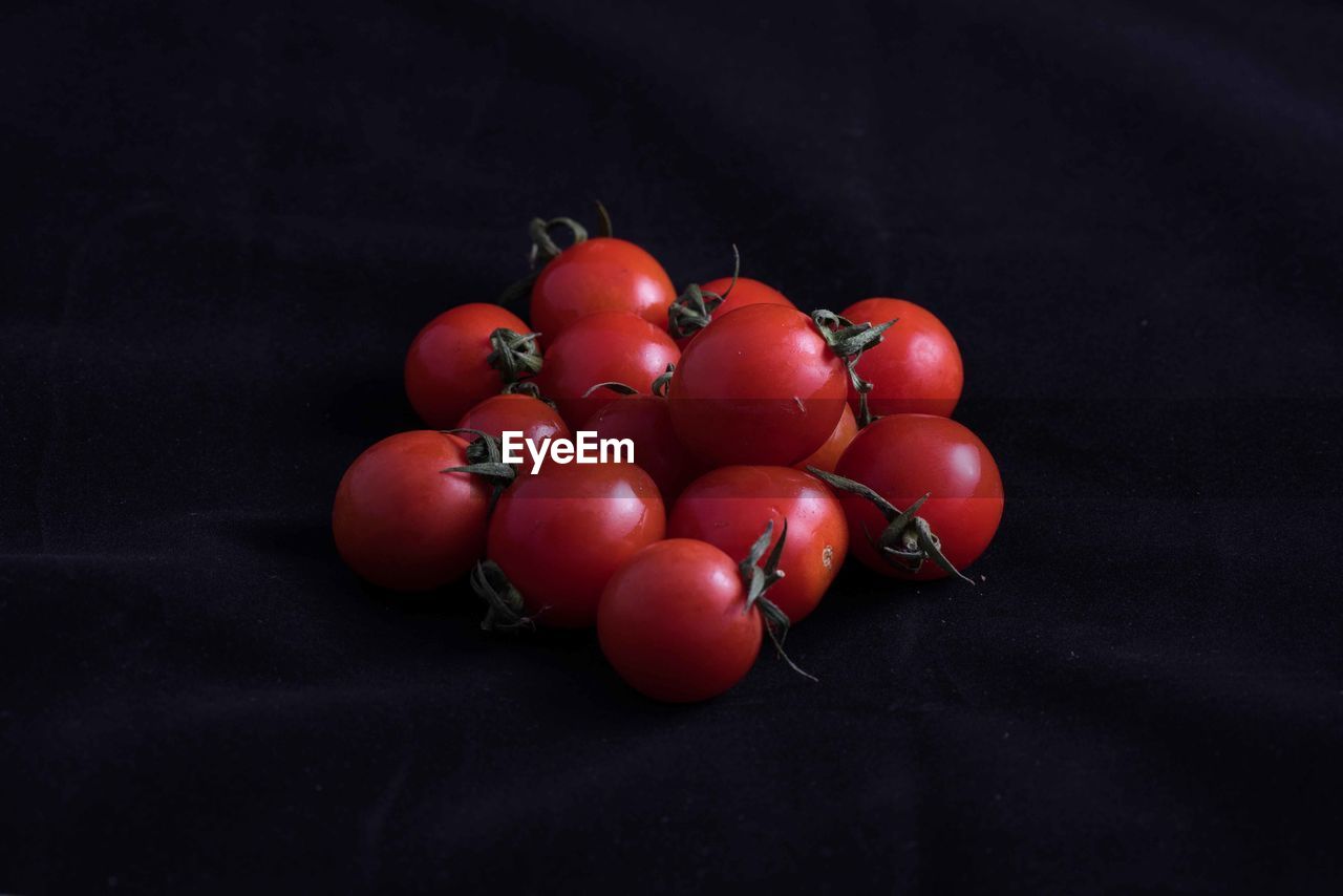 CLOSE-UP OF RED CHERRIES OVER BLACK BACKGROUND