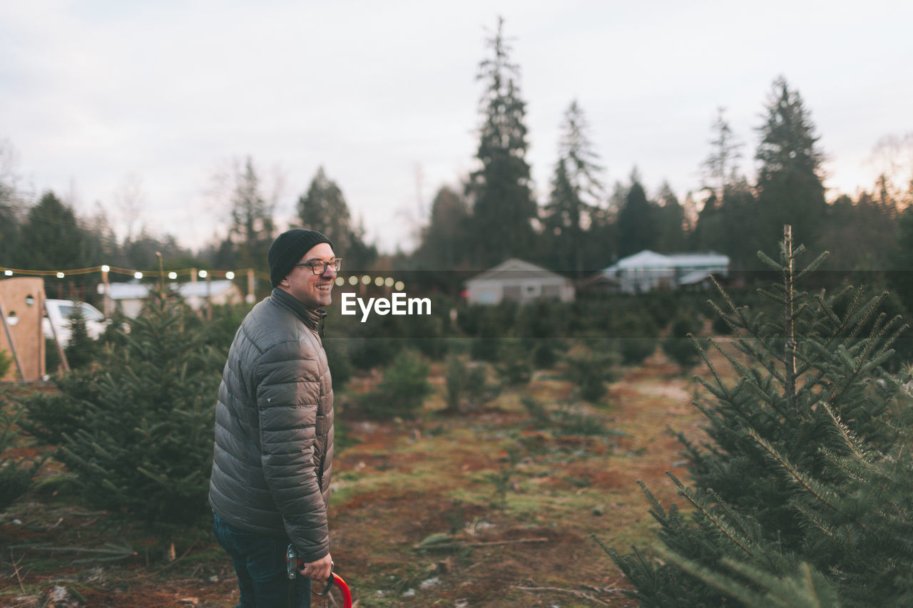 Side view of mature man standing on landscape against sky during winter