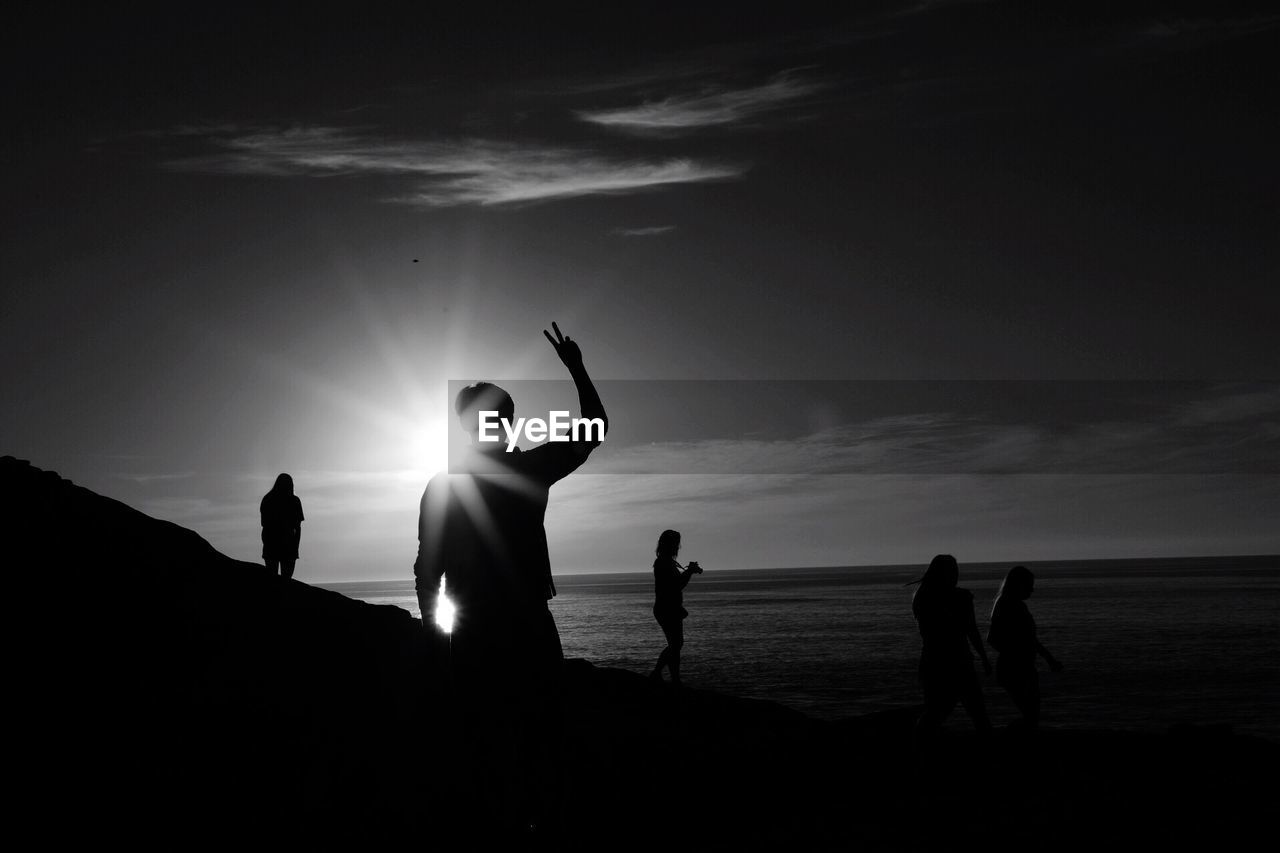 SILHOUETTE PEOPLE STANDING AT BEACH DURING SUNSET